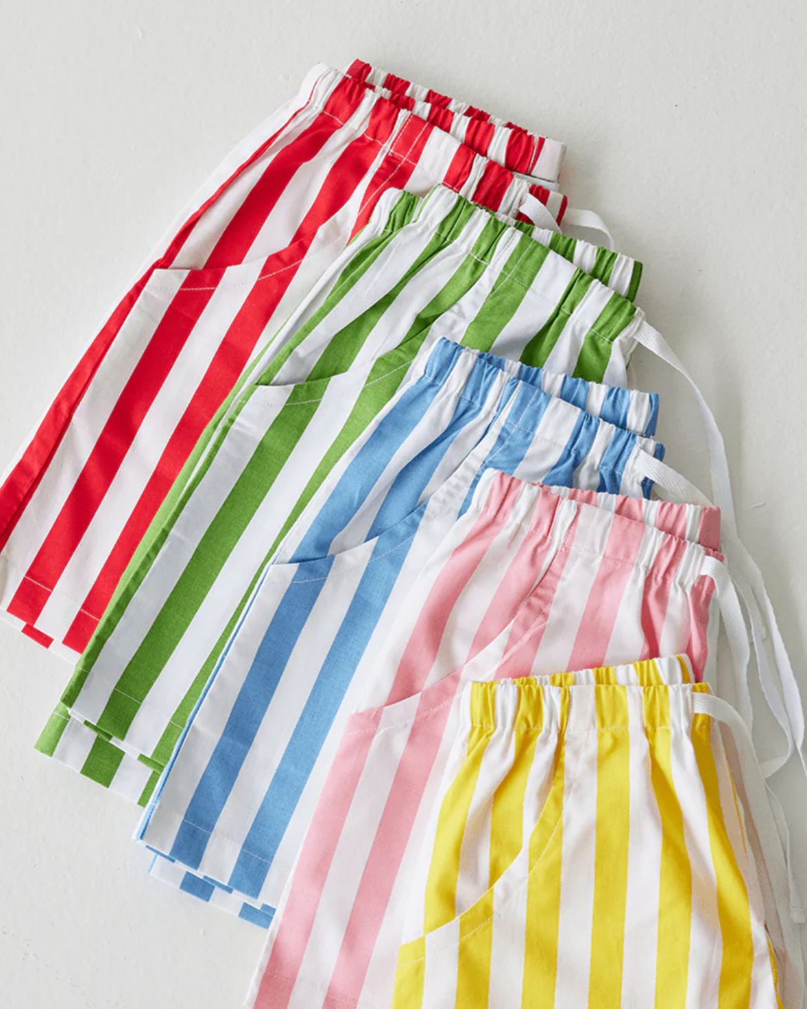 Set of colorful striped aprons on a light gray background